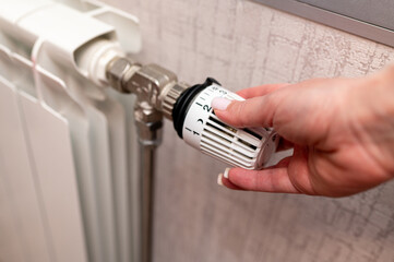 Female Hand Turning Radiator Thermostat Knob to Adjust Room Temperature for Home Energy Efficiency