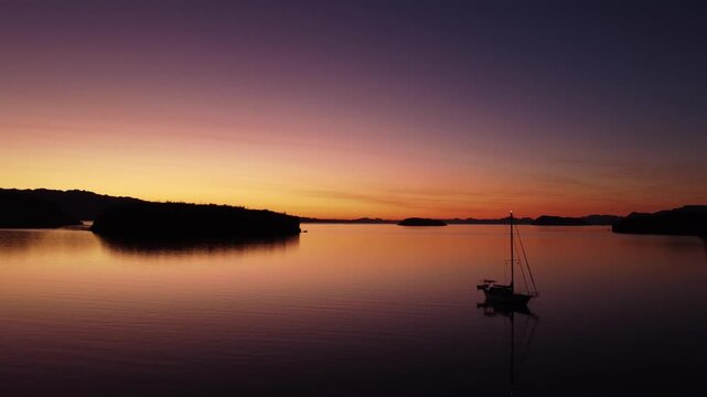 Early sunrise over ocean and anchored sail boat