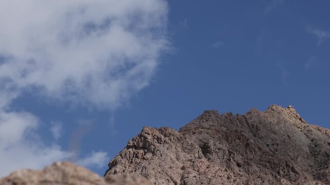 Clear blue sky with soft clouds over rocky ridge in Iran, minimal landscape background, calm nature scene, copy space, atmospheric outdoor footage
