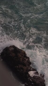 Close-up of white sea foam and splashing water on dark rocks, Madeira coast