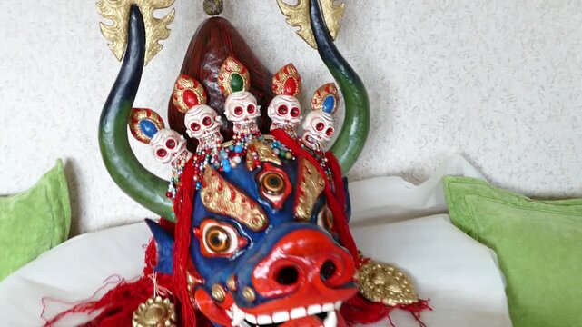 A big blue Mongolian mask of a angry Buddhist deity. Chojal is the god of death. It is depicted with a bull's head, three eyes and a crown of five skulls.