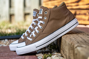 Fototapeta premium Brown Converse Chuck Taylor high top sneakers on wooden step outdoors