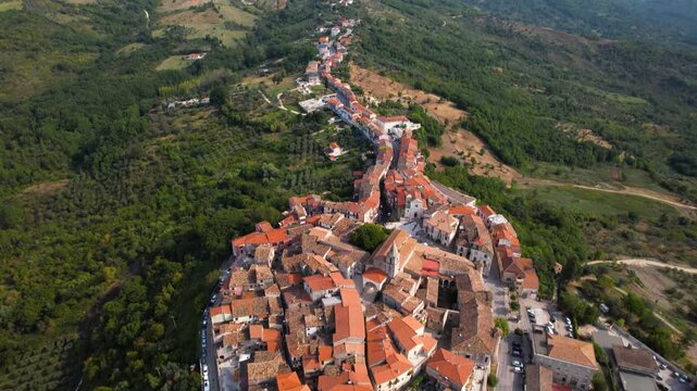 Fornelli aerial 4k view of medieval village in Italy with stone walls. Cinematic drone lift over borgo on green hills looking like a snake in Molise province. Historic fortifications and scenery