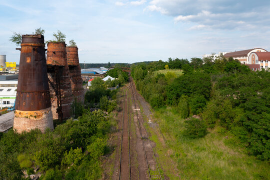 Aerial view of abandoned railway tracks in Kladno brownfield area with former Poldi steelworks complex visible in the distance. Post-industrial landscape in Czech Republic.
