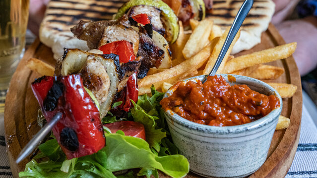 Grilled Meat Skewers with Fries and Sauce on Wooden Platter