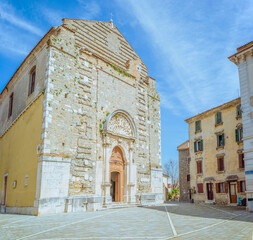 Fototapeta premium Buje, Istria, Croatia: Stone church facade with ornate entrance and adjacent buildings