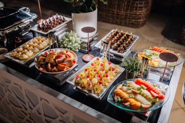 Fototapeta premium Assorted gourmet desserts and fresh fruit platters displayed elegantly on a buffet table with decorative elements and modern serving utensils in a stylish setting