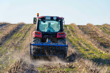 Fototapeta premium Farmer operating tractor cultivating field, preparing land for planting