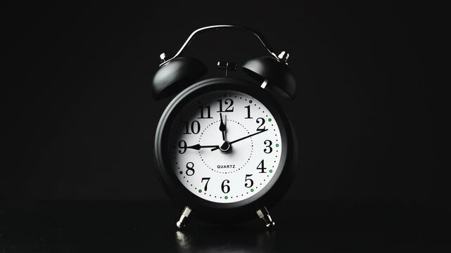Striking black clock elegantly ticks in dark setting, marking time. Time moving fast. Time concept. Table clock show running time. Close-up in 4K, UHD