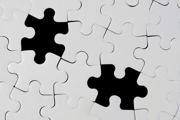 Fototapeta premium White Jigsaw Puzzle with Two Missing Pieces on Black Background