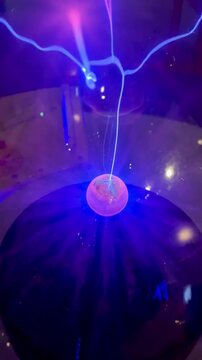 Close-up of a glowing plasma globe generating bright electric arcs inside a glass sphere. 