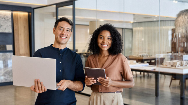 Young happy professional work team of two diverse confident female and male partners employees business people man and woman standing together in office looking at camera, corporate portrait.