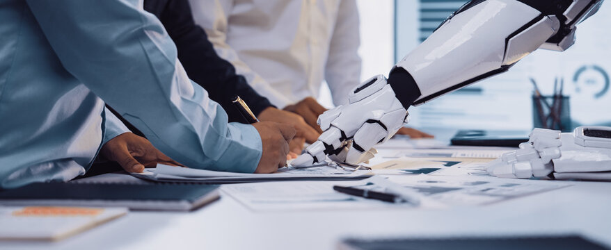 An engaging scene of collaboration in a modern office where human hands and a robot arm work together over documents, reflecting the future of innovative teamwork.Noogenesis