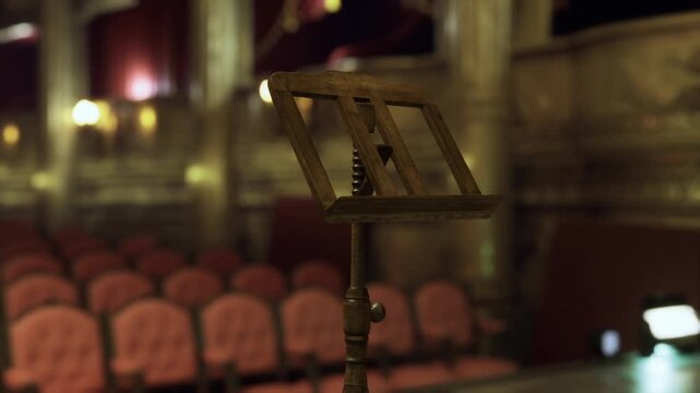 Close music stand with blurred seats and warm bokeh lighting, focused brass edges and sheet score hints, intimate rehearsal snapshot with nostalgic theater