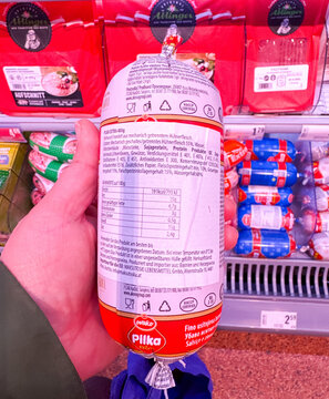 Villach, Austria - January 29, 2026: Hand holding a packaged sausage product labeled Pilka, nutritional information and ingredients visible on the back in a grocery store aisle