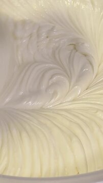 Creamy mixture being whipped in a bowl with visible swirling patterns and texture