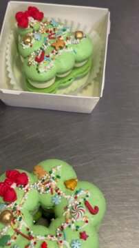 Festively decorated green macarons in boxes on metallic surface for holidays