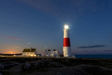 Naklejka premium Night photo of star trails over Portland Bill lighthouse in Dorset