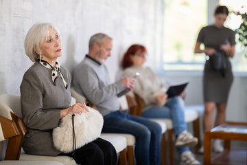 Obraz premium Elderly man and woman in casual clothes waiting for his turn on chair in reception