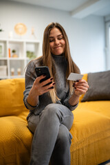 Obraz premium Young woman shopping online using phone and credit card