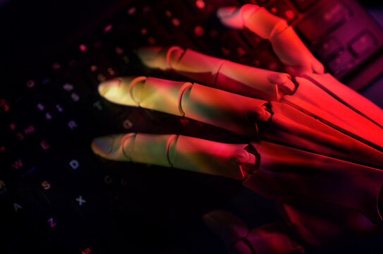 Robotic hand typing on a keyboard in red lighting