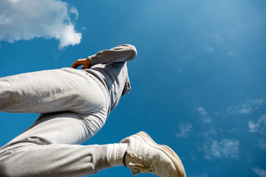 Young man running under a bright blue sky with clouds