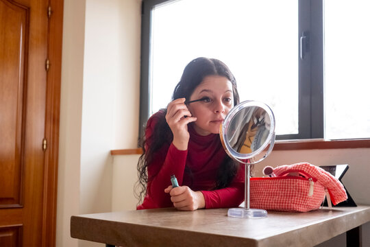 Woman applying mascara in front of a mirror