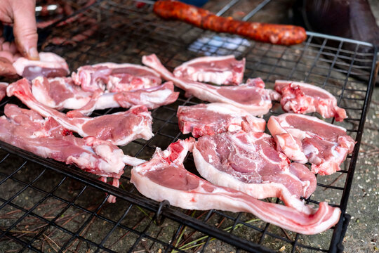 Lamb chops arranged on a grill, ready to be cooked over an open fire