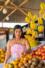 Obraz premium Woman selecting fresh fruit at local market stall