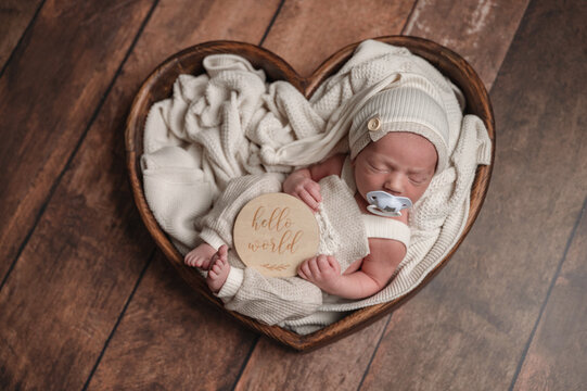 Peaceful newborn baby in heart-shaped basket