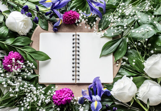 Open notebook framed by colorful flowers and greenery