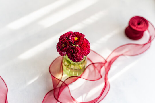 Spring flowers with red ribbon on a bright table