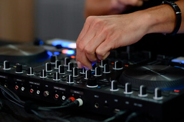 DJ adjusts sound levels on professional audio mixer during performance