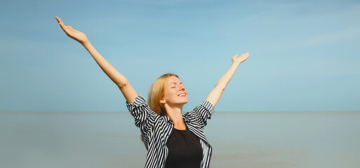 Obraz premium Summer vacation, happy inspired young woman raising her hands up on the beach, relaxed girl on sea