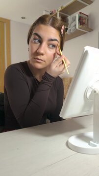 Young caucasian woman applying makeup in front of mirror