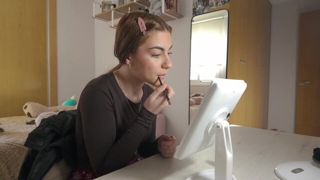 Young woman applying lip liner in front of a mirror