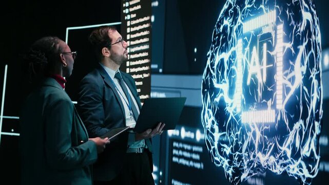 Engineering team looks at AI machine learning self writing code on screen, autonomy concept. Teamworking colleagues reviewing self sustaining artificial intelligence model, doing brainstorming