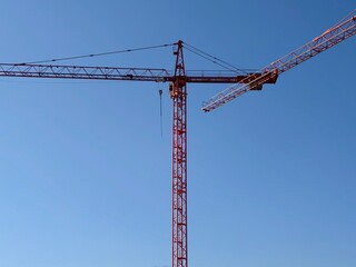 Construction crane over cityscape. Vivid red tower crane signifies large scale urban development project