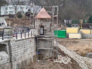 Scaffolding covers historic riverside tower. Stone foundation exposed during renovation of turret © Vladimir
