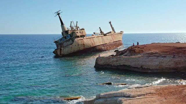 EDRO III shipwreck half sunk near the rocky Paphos coastline in Cyprus, standing as an abandoned hulk along the Mediterranean Sea, attracting tourists exploring the area. Aerial view drone flight