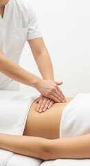 Professional therapist performing abdominal massage on a woman lying on a treatment table covered with a white towel