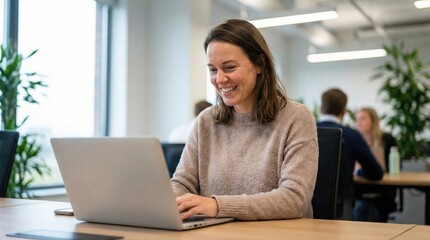 Smiling businesswoman working on laptop in modern office