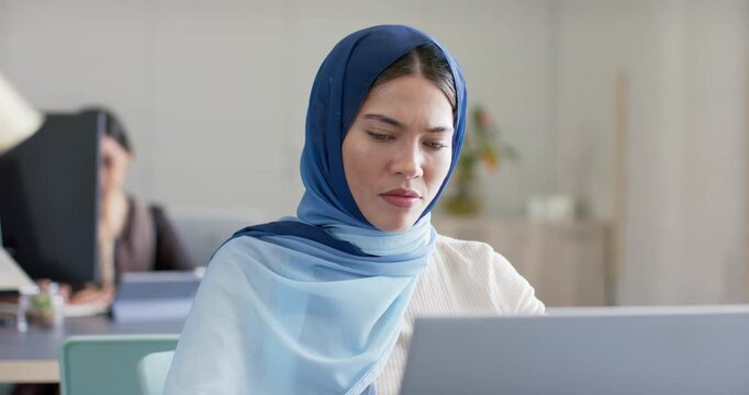 Indian woman in hijab at desk reading content on laptop, scrolling, typing and fixing inconsistency