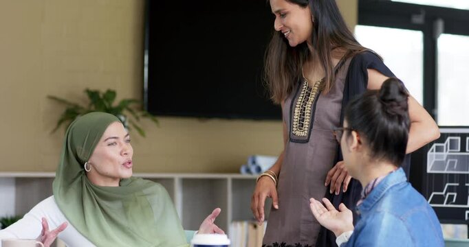 Standing Indian woman leaning over model in conference room as team raising hands, guiding design