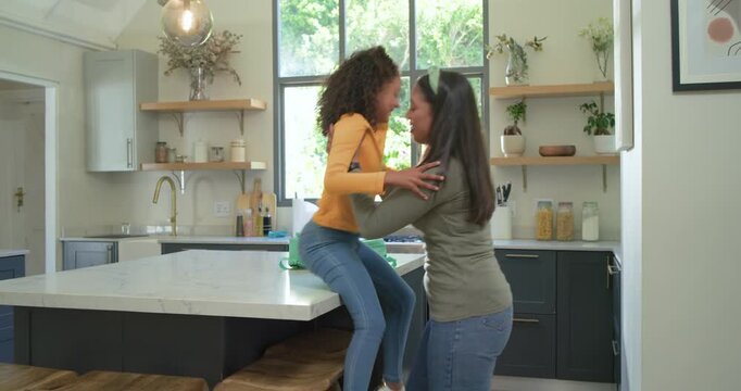 Mother and daughter on kitchen island mom lowering stool fitting mint backpack preparing for school