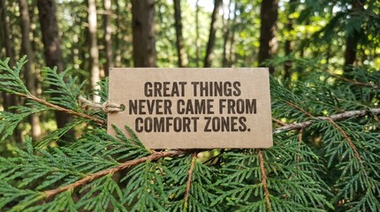Motivational quote on a tag hanging from a green tree branch in a sunlit forest