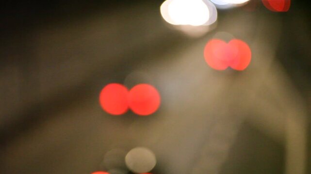 The film captures an artistic, out-of-focus view of city traffic at night. Blurred headlights and taillights transform into glowing orbs of red, white, and yellow, creating a dreamy bokeh effect. The 