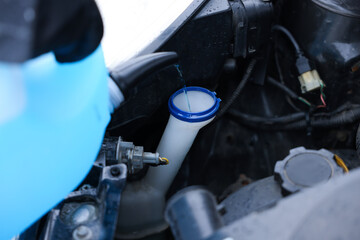 Obraz premium Woman filling car radiator with antifreeze outdoors, closeup. Space for text