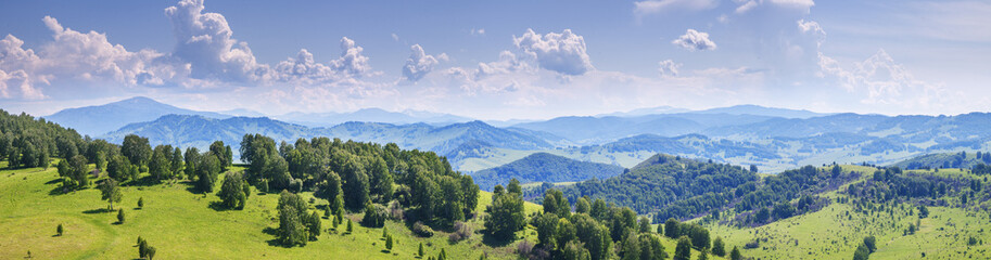 Fototapeta premium Panoramic view of a summer day in the mountains, green mountain slopes and hills