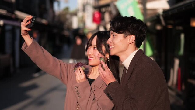 柴又の観光地でスマートフォンで自撮りするカップル